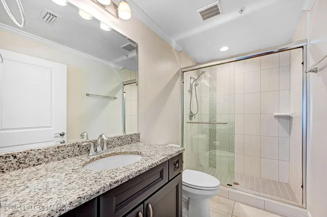 a bathroom with a granite countertop sink a toilet a mirror and shower