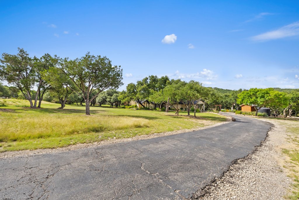 23644 Nameless Road Leander, TX 78641 - Photo 4 of 40 A private, paved driveway winds through lush greenery leading to a secluded residence.