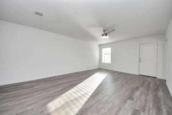 a view of empty room with wooden floor and fan