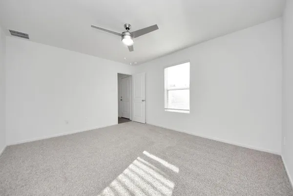 an empty room with a fan & a window