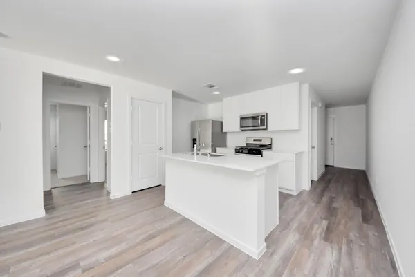 a kitchen with wooden floor and white cabinets