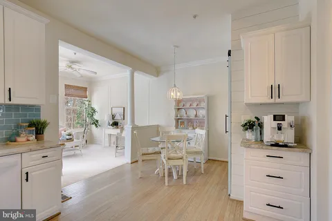 a kitchen with white cabinets and dining table chair with wooden floor