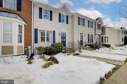 a view of a white house with a bench in front of house
