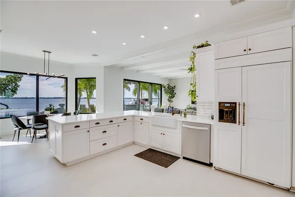 a large white kitchen with granite countertop a sink and white cabinets