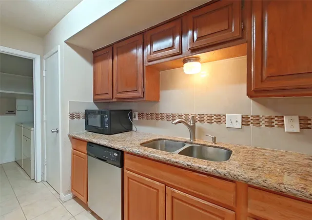 a kitchen with granite countertop a sink and a wooden cabinets