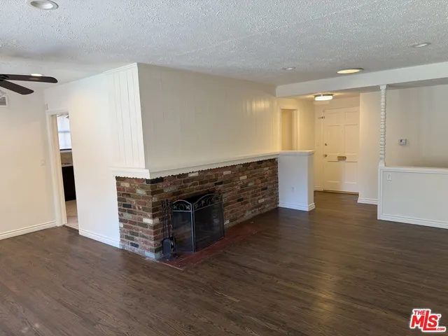 a view of kitchen and empty room with wooden floor