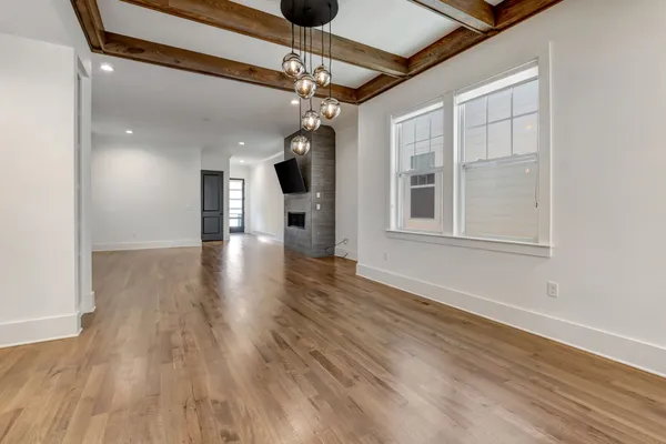 a view of an empty room with wooden floor a ceiling fan and windows