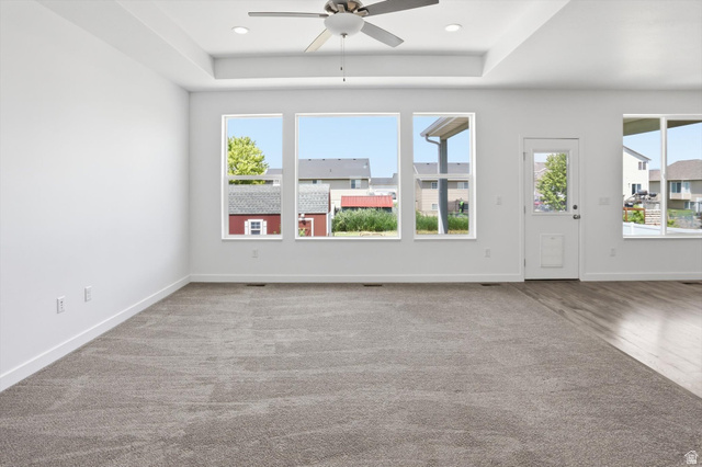 3636 West 910 South Syracuse, UT 84075 - Photo 16 of 70 Spacious room featuring a tray ceiling with a ceiling fan, recessed lighting, and a combination of carpet and wood-finish flooring