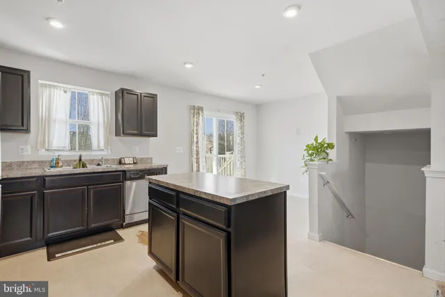 a kitchen with stainless steel appliances kitchen island granite countertop a sink and a stove top oven with wooden floor