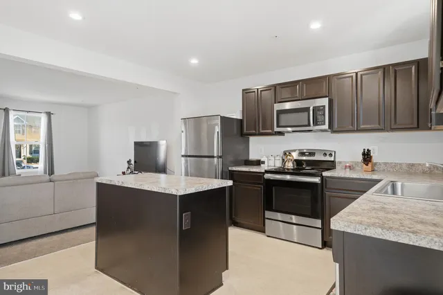 a kitchen with kitchen island granite countertop appliances cabinets and a sink