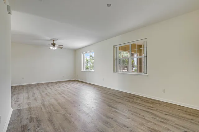 an empty room with windows and fan