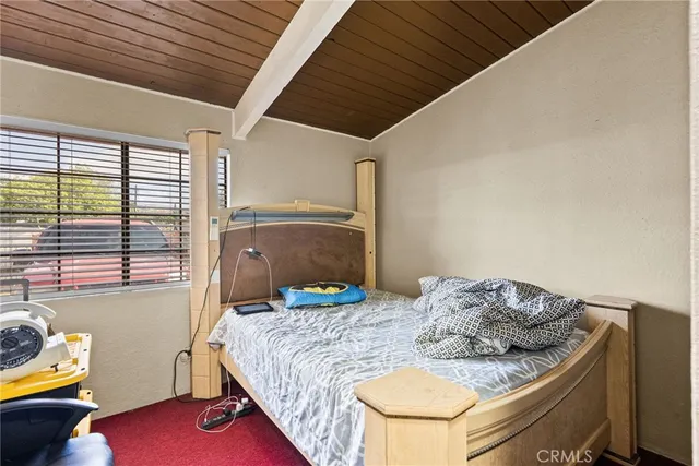 a bedroom with a bed and a dresser next to a window