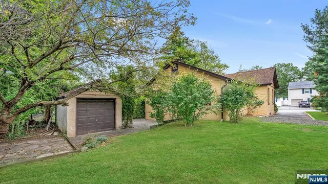 a front view of a house with a garden and trees