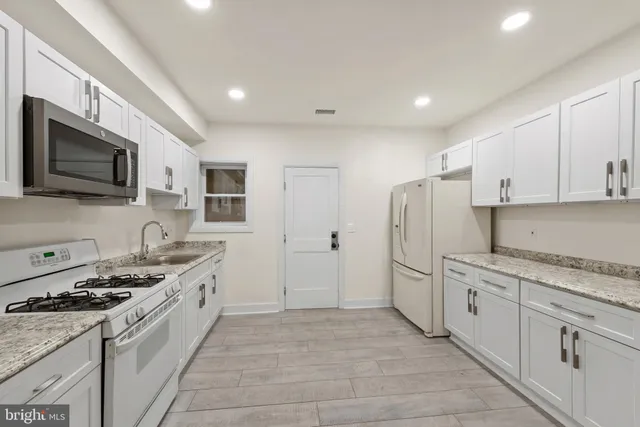 a kitchen with stainless steel appliances granite countertop a stove a sink and a refrigerator