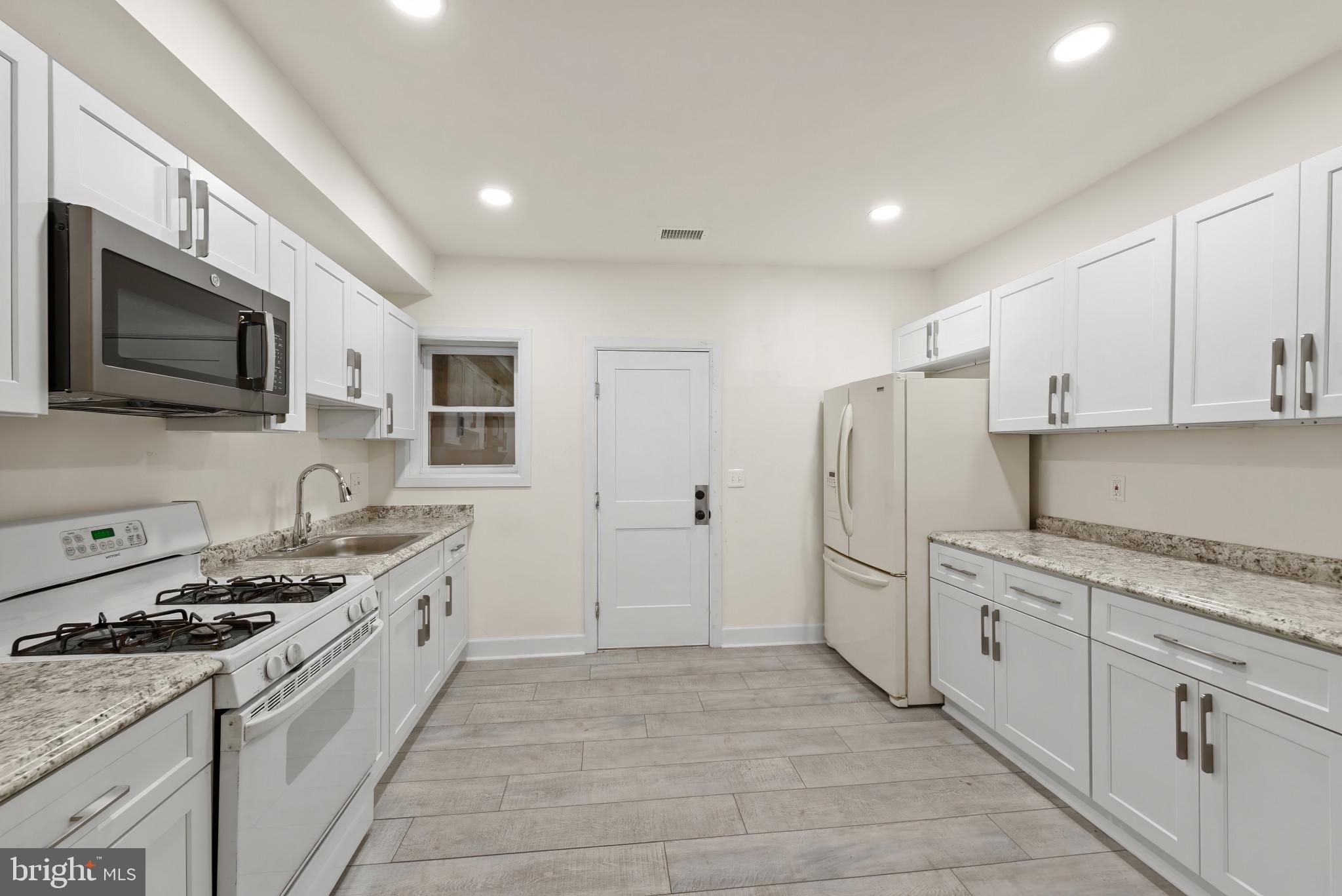 2419 Baker Street Baltimore, MD 21216 - Photo 12 of 40 a kitchen with stainless steel appliances granite countertop a stove a sink and a refrigerator