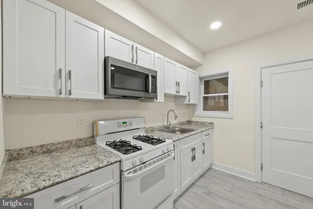 a kitchen with stainless steel appliances granite countertop white cabinets sink and dishwasher