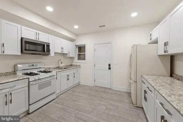 a kitchen with granite countertop a stove top oven sink and microwave