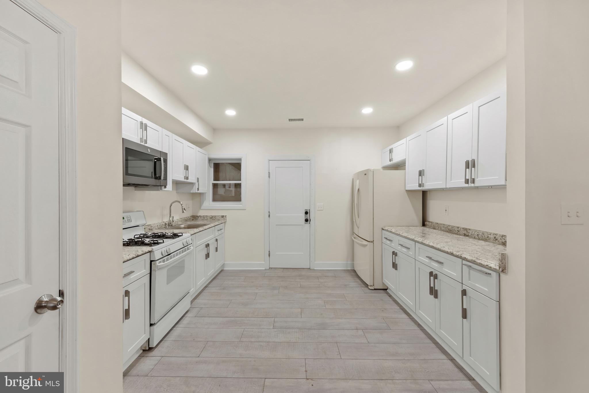 2419 Baker Street Baltimore, MD 21216 - Photo 15 of 40 a large kitchen with stainless steel appliances granite countertop a stove and a refrigerator