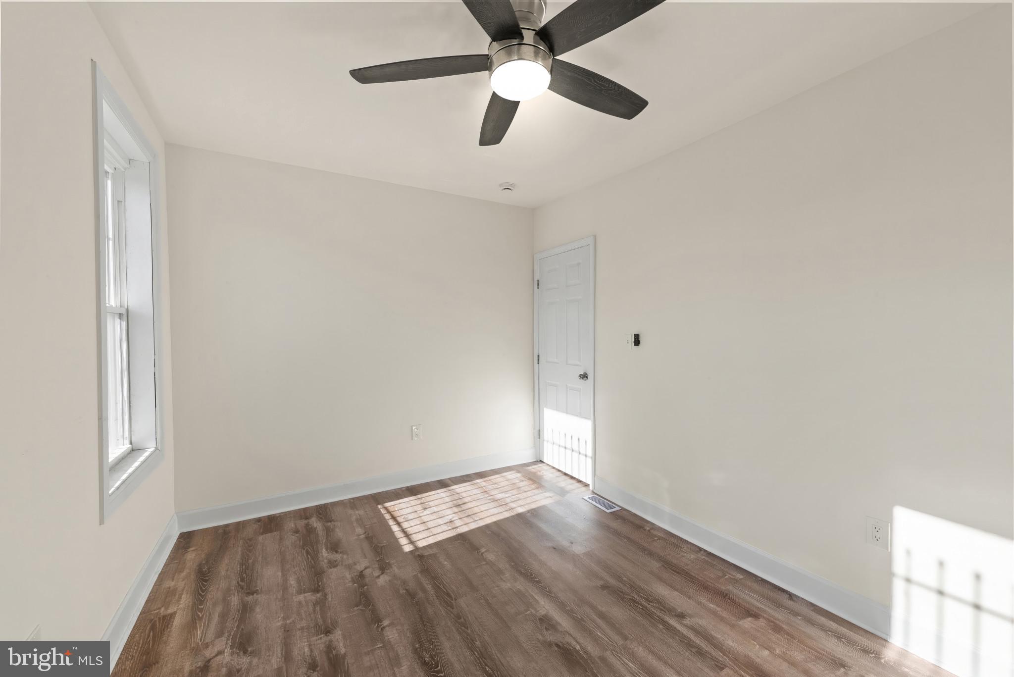 2419 Baker Street Baltimore, MD 21216 - Photo 20 of 40 an empty room with wooden floor ceiling fan and windows