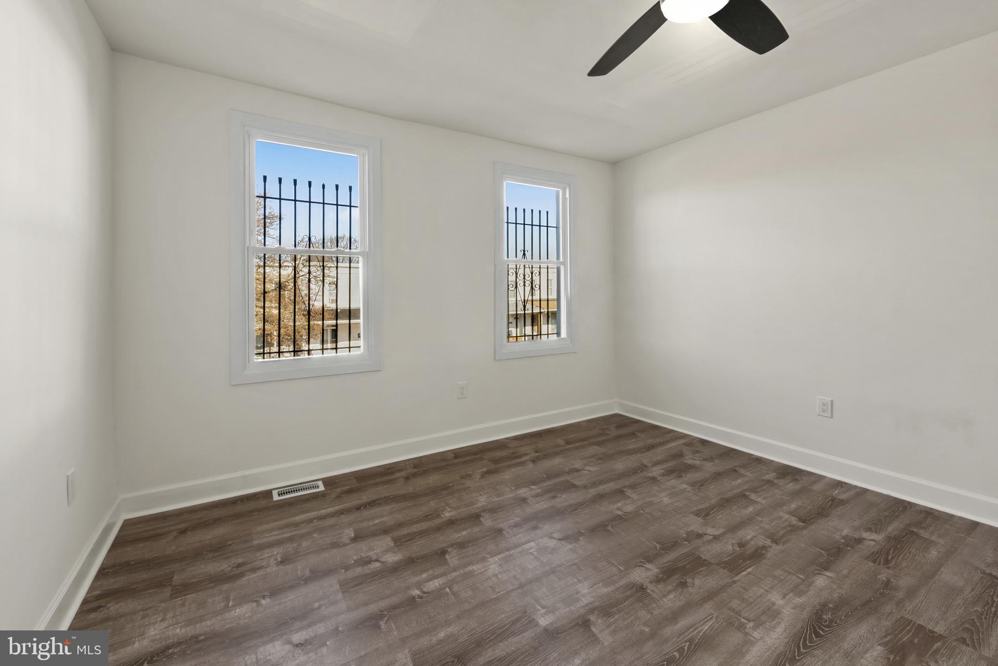 2419 Baker Street Baltimore, MD 21216 - Photo 32 of 40 an empty room with wooden floor ceiling fan and windows