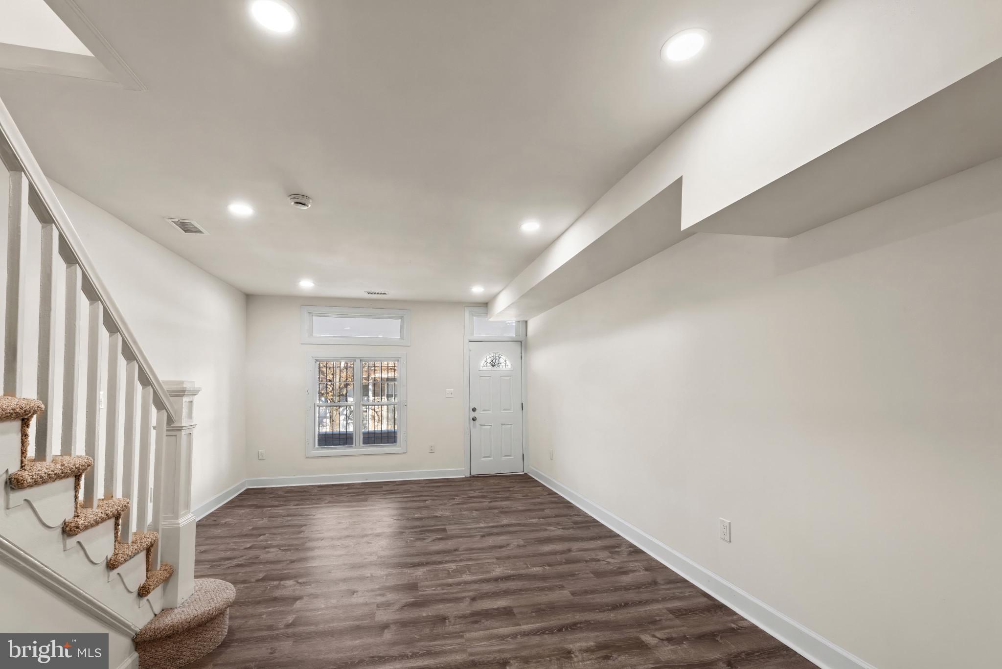 2419 Baker Street Baltimore, MD 21216 - Photo 5 of 40 a view of an empty room with a window and wooden floor