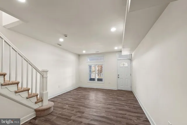 a view of an empty room with wooden floor and entryway