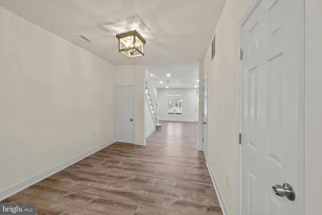 a view of a hallway with wooden floor and a chandelier