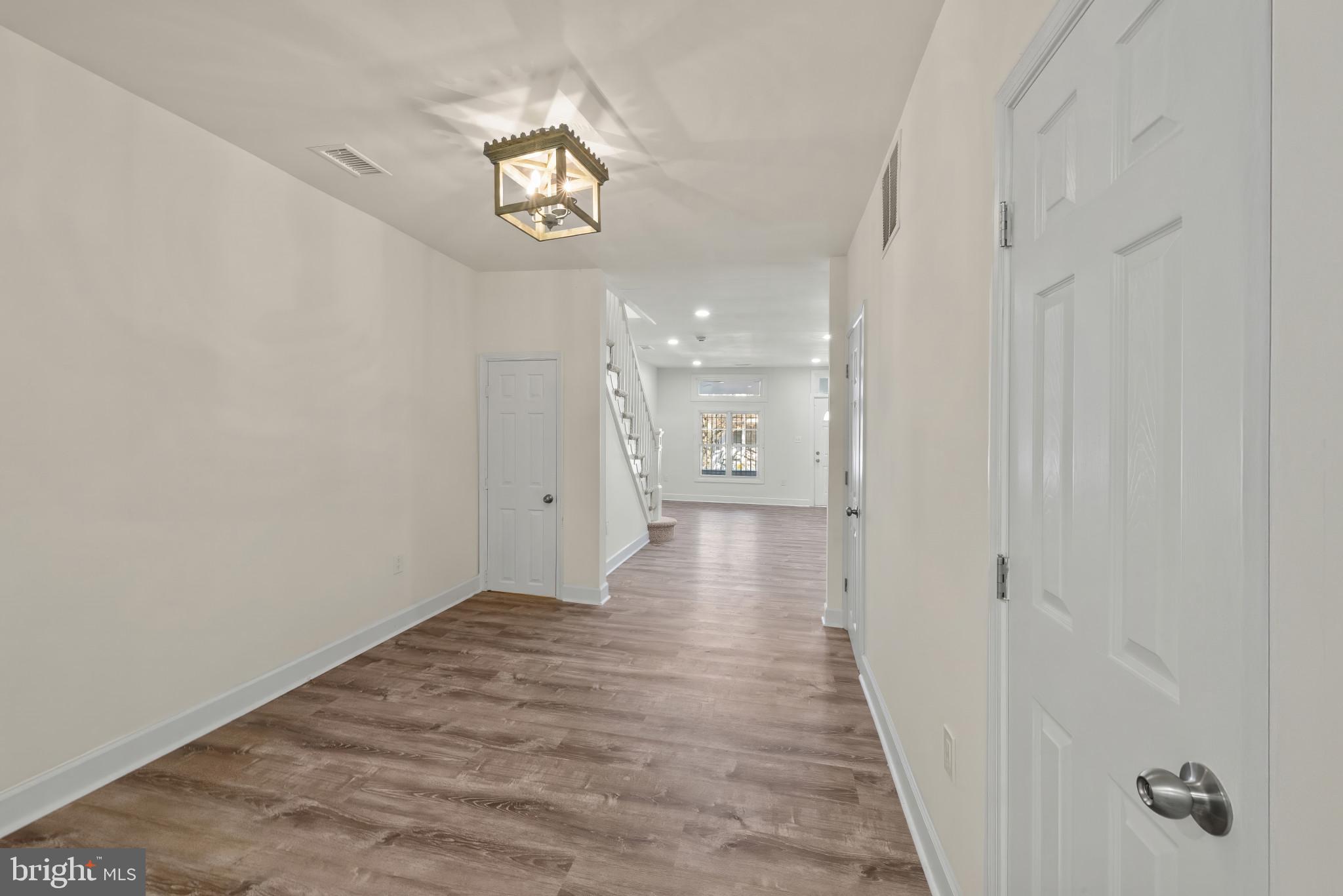 2419 Baker Street Baltimore, MD 21216 - Photo 9 of 40 a view of a hallway with wooden floor and a chandelier