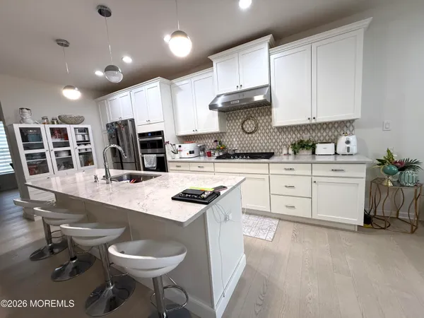a kitchen with stainless steel appliances a sink a stove a refrigerator cabinets and chairs