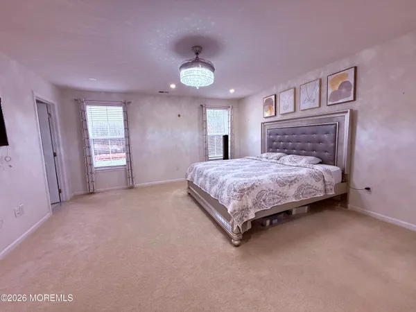 a bedroom with a bed chandelier and a window
