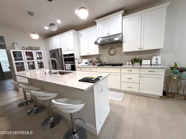 a kitchen with stainless steel appliances granite countertop a table chairs sink and cabinets