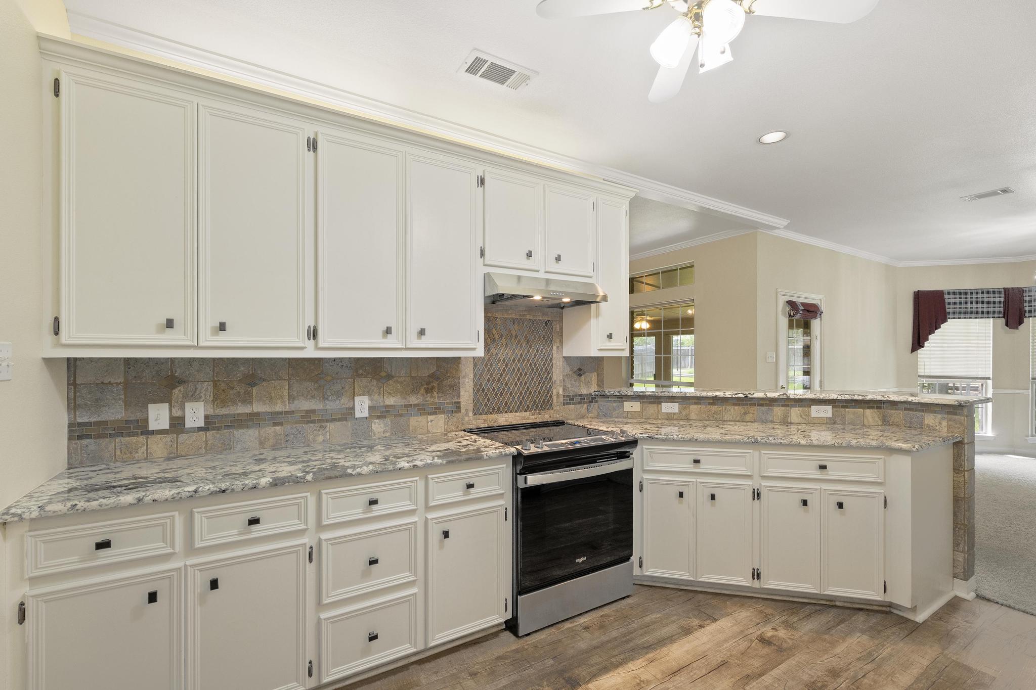 1906 Meadow Ridge Drive Taylor, TX 76574 - Photo 6 of 24 a kitchen with granite countertop white cabinets and stainless steel appliances