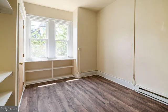 an empty room with wooden floor and window