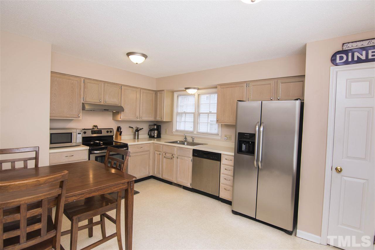 4416 Emmit Drive Raleigh, NC 27604 - Photo 9 of 28 a kitchen with a refrigerator a stove top oven a sink a dining table and chairs