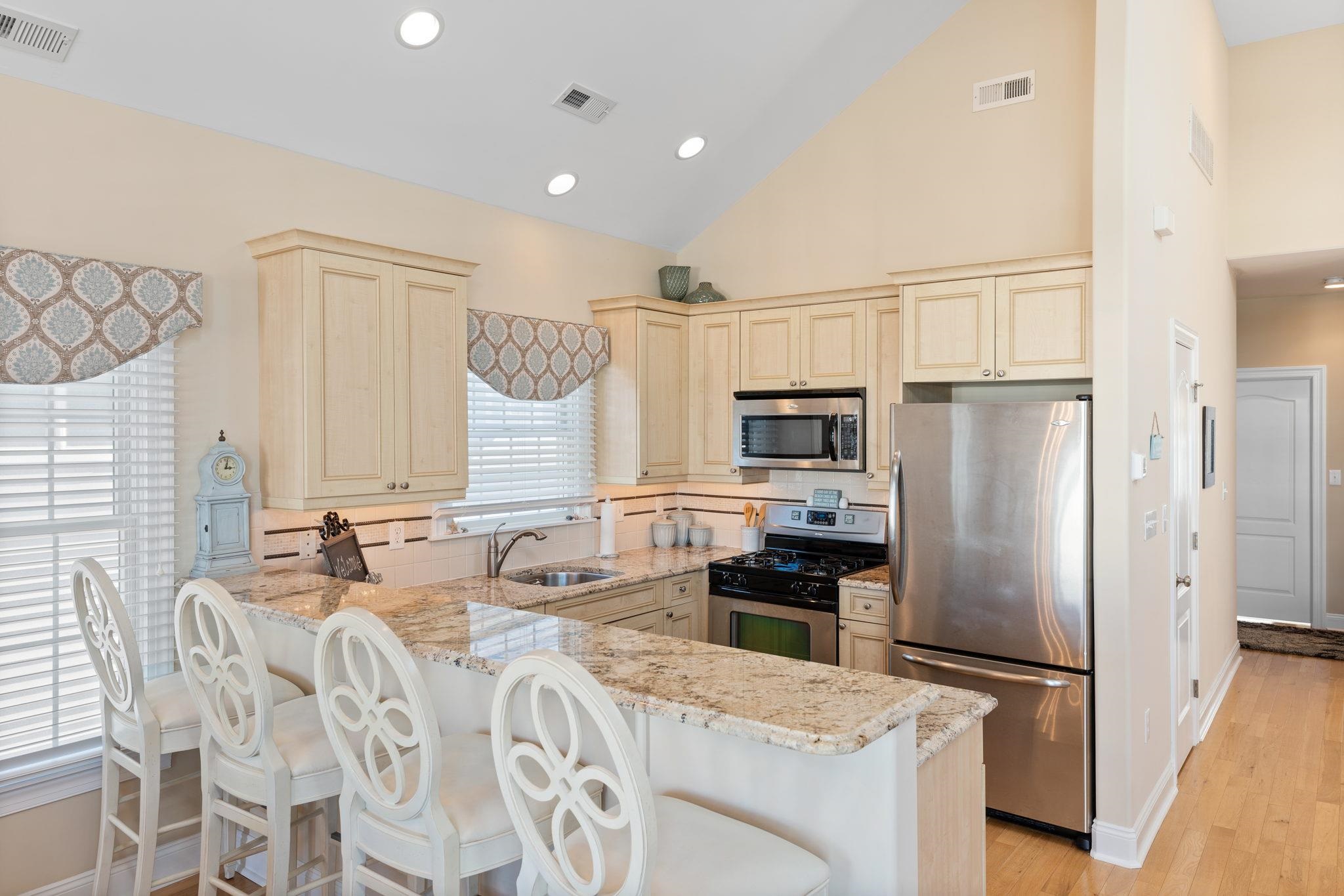 244 23rd Street Avalon, NJ 08202 - Photo 5 of 21 a kitchen with stainless steel appliances granite countertop a refrigerator a stove a sink dishwasher and white cabinets with wooden floor