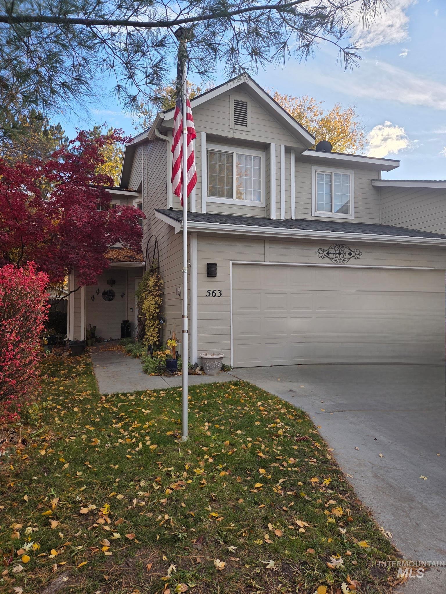 Traditional-style house featuring an attached garage, driveway, and a front yard