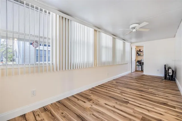 a view of a bedroom with wooden floor and a ceiling fan