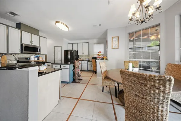 a kitchen with stainless steel appliances granite countertop a stove top oven a sink dishwasher a dining table and chairs with wooden floor