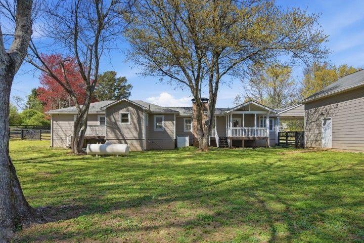 2215 Roper Road Cumming, GA 30028 - Photo 12 of 24 a big white house with a big yard and large trees