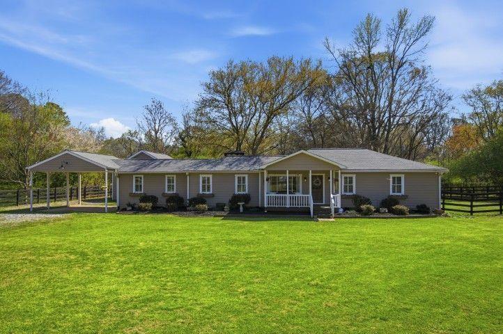 2215 Roper Road Cumming, GA 30028 - Photo 3 of 24 a view of a house with a big yard and large trees