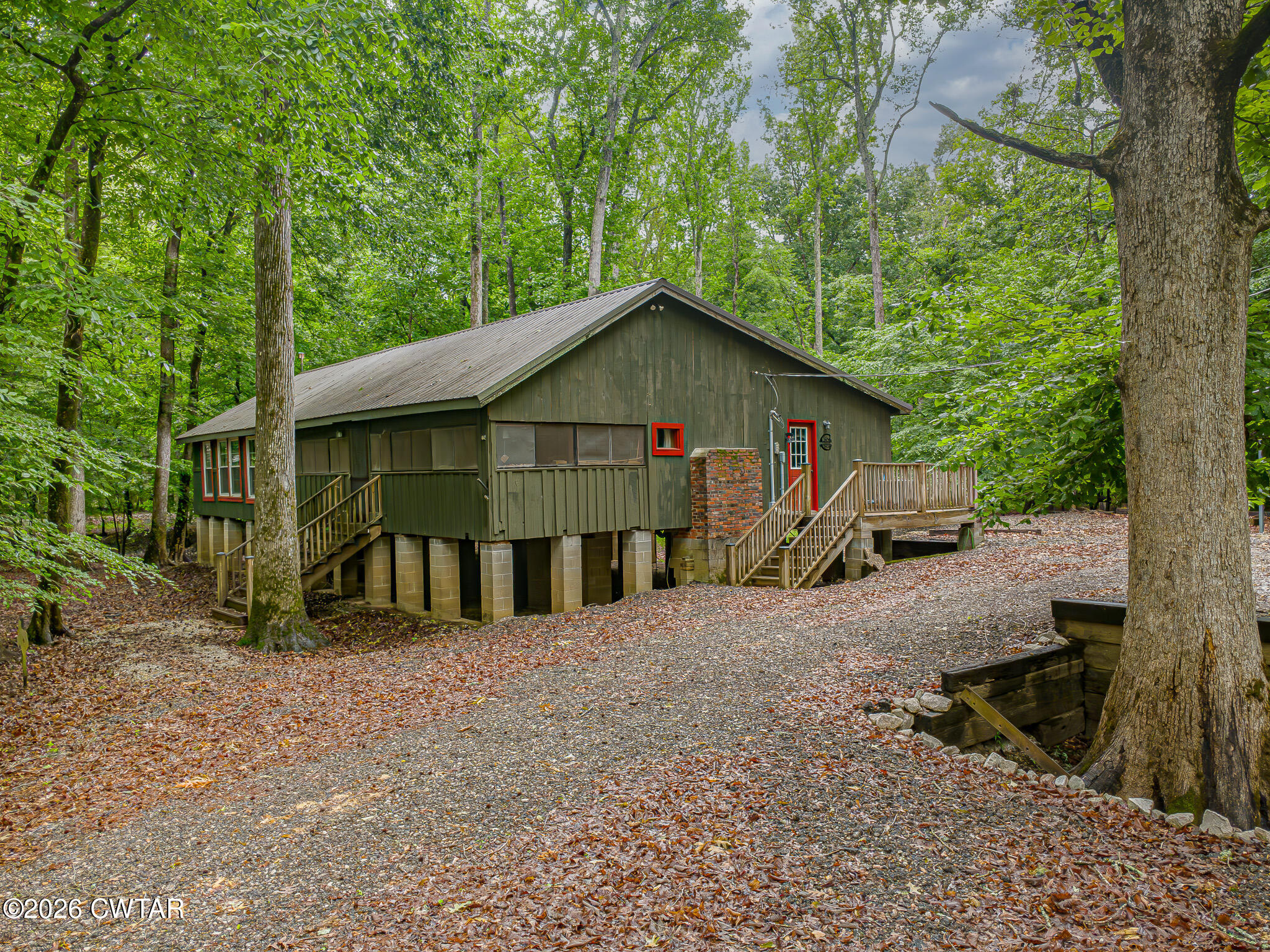 445 Wesley Lake Road Brownsville, TN 38012 - Photo 1 of 21 a view of a wooden house with large trees and lawn chairs