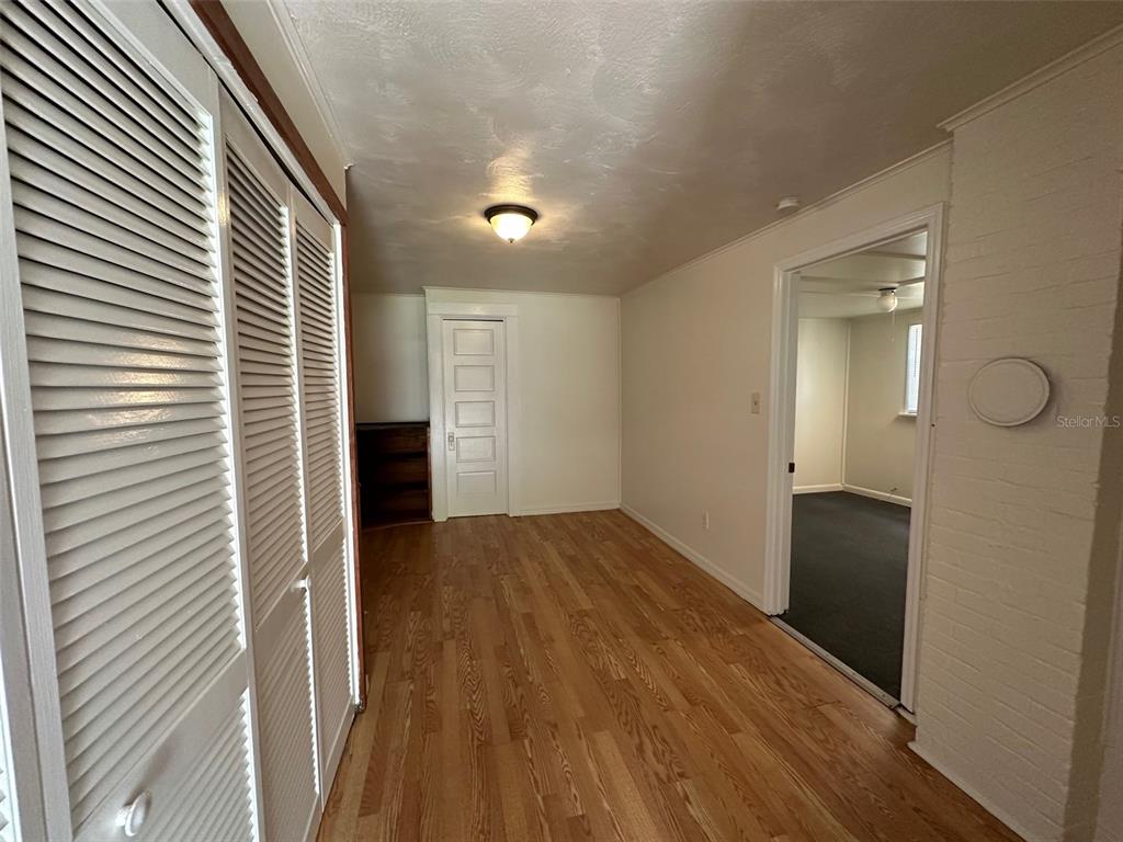 407 Poinsettia Road Daytona Beach, FL 32118 - Photo 4 of 10 a view of a hallway to an empty room with wooden floor and a window