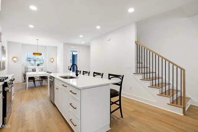 a large white kitchen with sink a stove a dining table and chairs