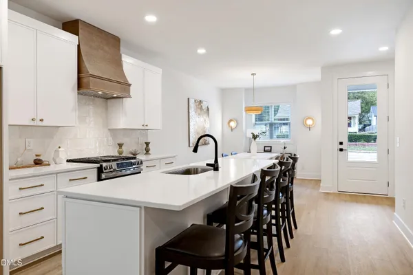 a kitchen with stainless steel appliances a table chairs and a stove top oven
