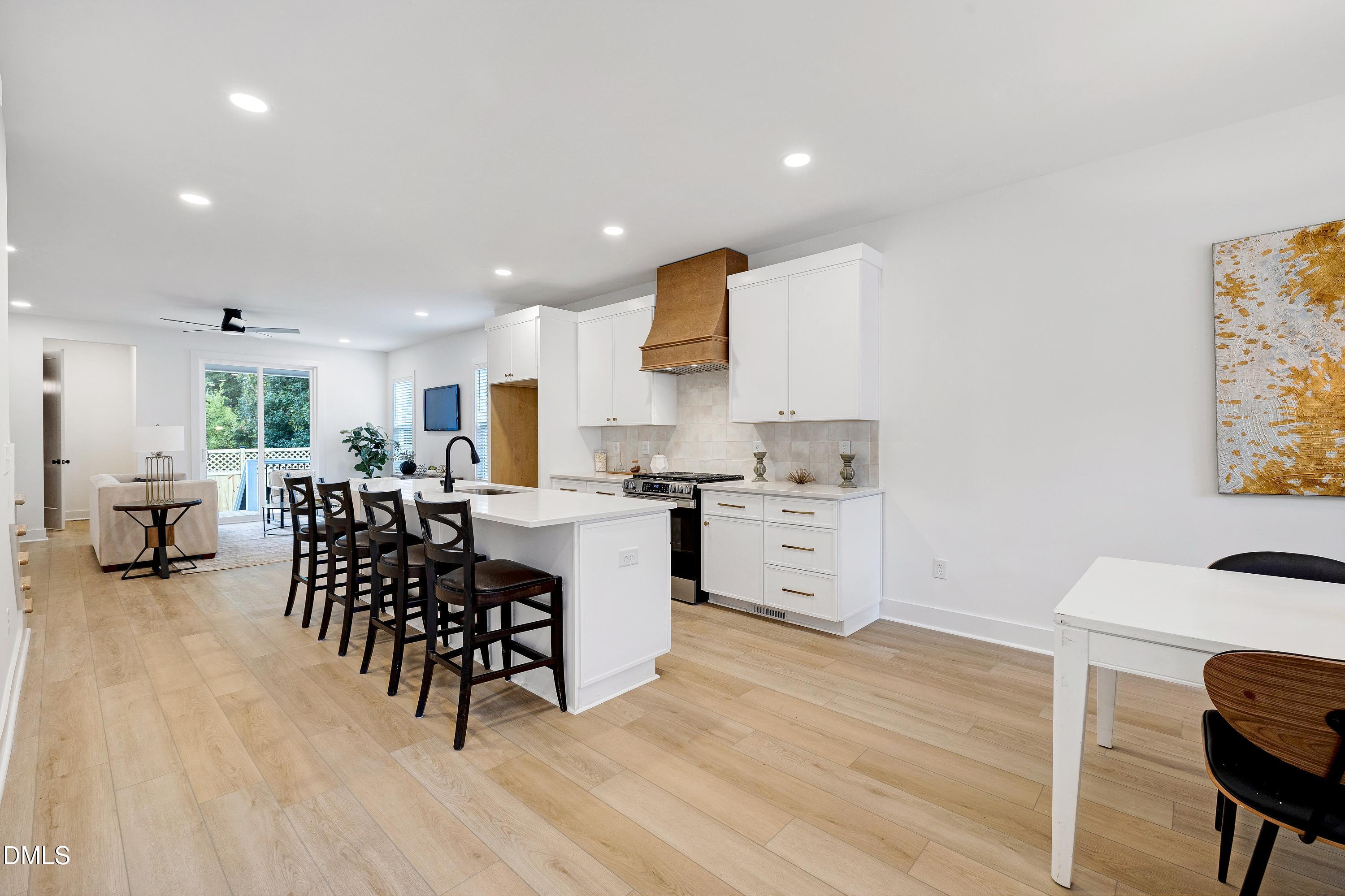 1418 Joe Louis Avenue Raleigh, NC 27610 - Photo 6 of 49 a kitchen with a dining table chairs and white appliances with wooden floor