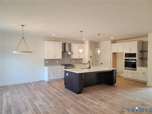 a large kitchen with stainless steel appliances a large counter top a stove a chimney a sink and a refrigerator