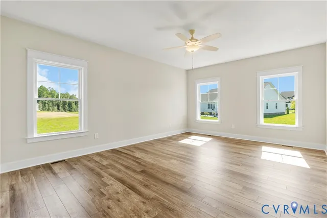 a view of an empty room with window and wooden floor