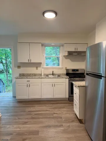 a kitchen with granite countertop a sink cabinets and wooden floor