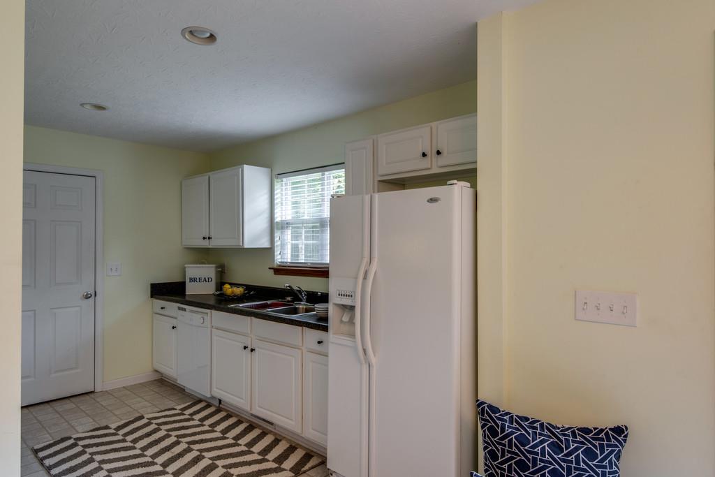 1427 St Paul Road Charlotte, TN 37036 - Photo 12 of 27 a kitchen with granite countertop a refrigerator a sink and white cabinets