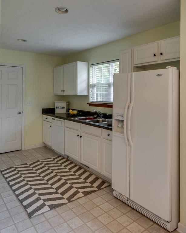1427 St Paul Road Charlotte, TN 37036 - Photo 13 of 27 a kitchen with a refrigerator a stove a sink and cabinets